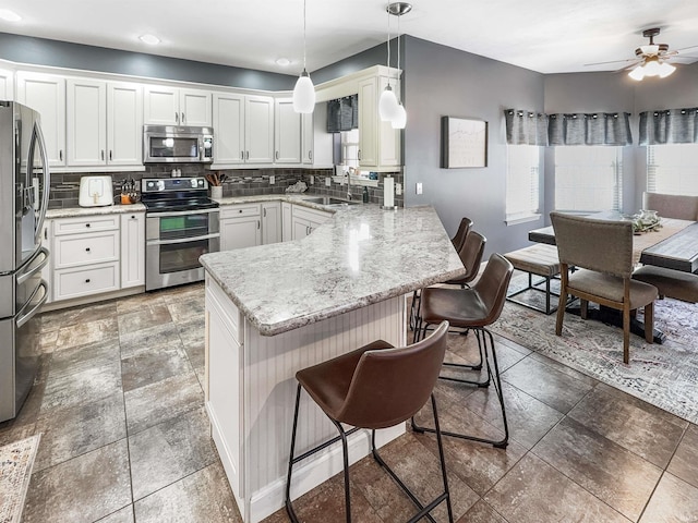 kitchen with tasteful backsplash, a breakfast bar, a peninsula, stainless steel appliances, and a sink