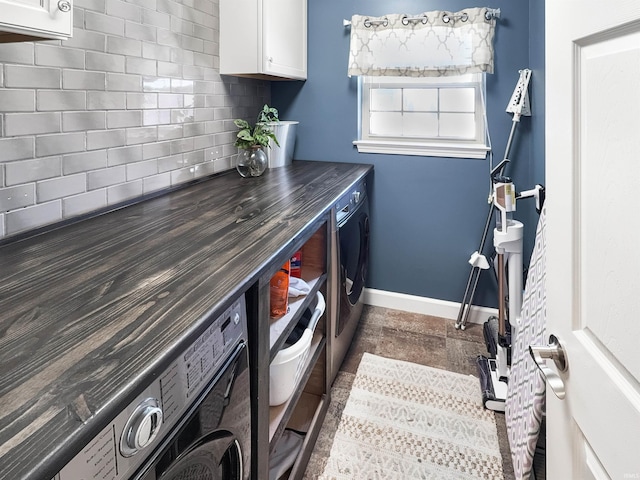 clothes washing area featuring washer and clothes dryer, cabinet space, and baseboards