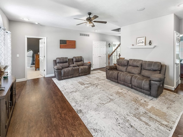 living area with baseboards, visible vents, dark wood finished floors, a ceiling fan, and stairs