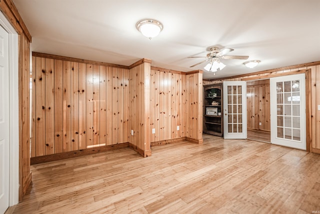 empty room featuring hardwood / wood-style flooring, ceiling fan, french doors, and wood walls