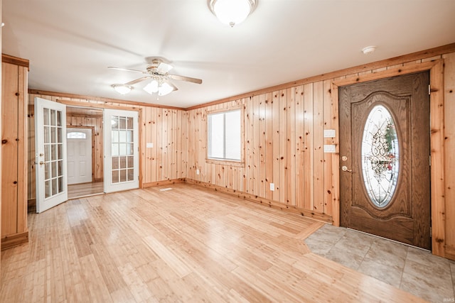 entryway featuring wood walls, ceiling fan, and french doors