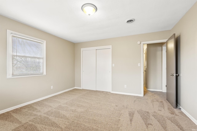 unfurnished bedroom with light colored carpet and a closet