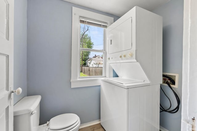 laundry area featuring stacked washing maching and dryer and hardwood / wood-style floors