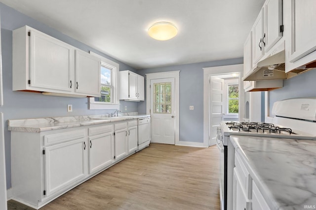 kitchen with white appliances, light stone countertops, light wood-type flooring, white cabinetry, and sink