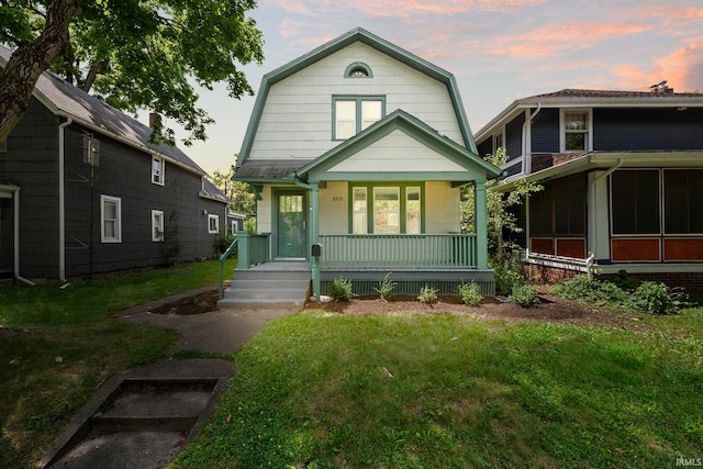 view of front of property featuring a lawn, covered porch, and a sunroom