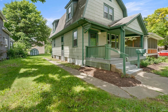 view of property exterior with covered porch, a lawn, and a shed