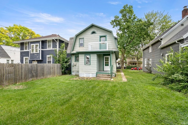 rear view of house featuring a balcony and a yard