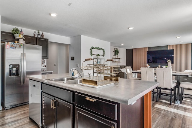 kitchen with stainless steel appliances, a kitchen island with sink, dark brown cabinetry, and sink