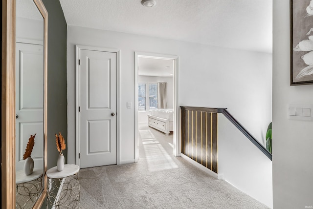 hall featuring a textured ceiling and carpet flooring