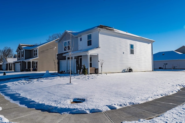 snow covered back of property with a garage