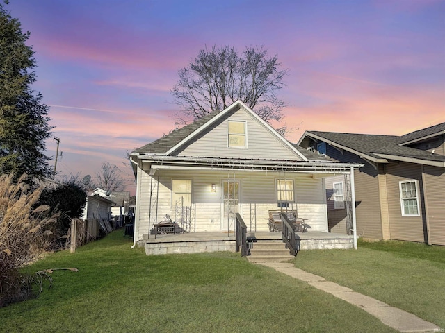 bungalow featuring covered porch and a yard