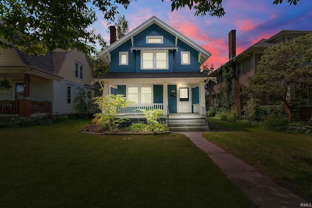 view of front of property with covered porch and a lawn