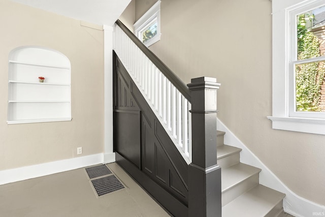 staircase featuring built in features, tile patterned floors, and a wealth of natural light