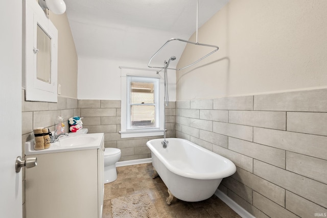 bathroom featuring toilet, vanity, and tile walls