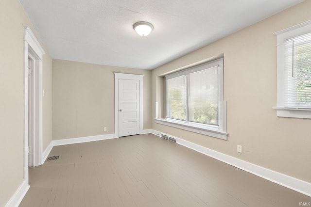 unfurnished bedroom with hardwood / wood-style floors, a closet, and multiple windows