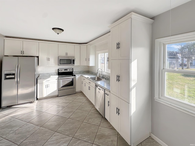 kitchen featuring a healthy amount of sunlight, stainless steel appliances, light tile patterned floors, white cabinets, and sink