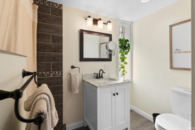 bathroom with toilet, wood-type flooring, and vanity