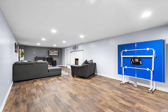 living room with a brick fireplace and hardwood / wood-style flooring