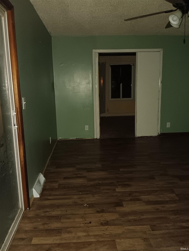 empty room featuring dark hardwood / wood-style flooring, a textured ceiling, and ceiling fan