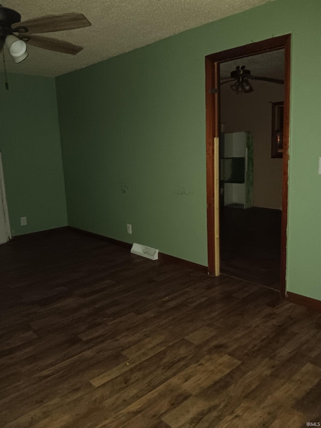 unfurnished room with ceiling fan, dark wood-type flooring, and a textured ceiling