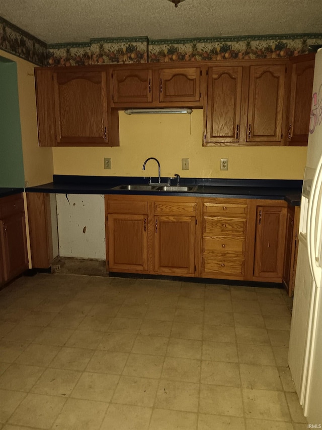 kitchen featuring sink, white fridge, and a textured ceiling