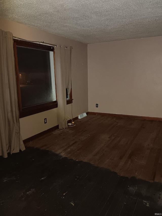 spare room with a textured ceiling and dark hardwood / wood-style flooring