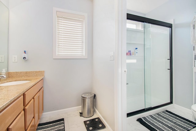 bathroom with a healthy amount of sunlight, vanity, a shower with shower door, and toilet