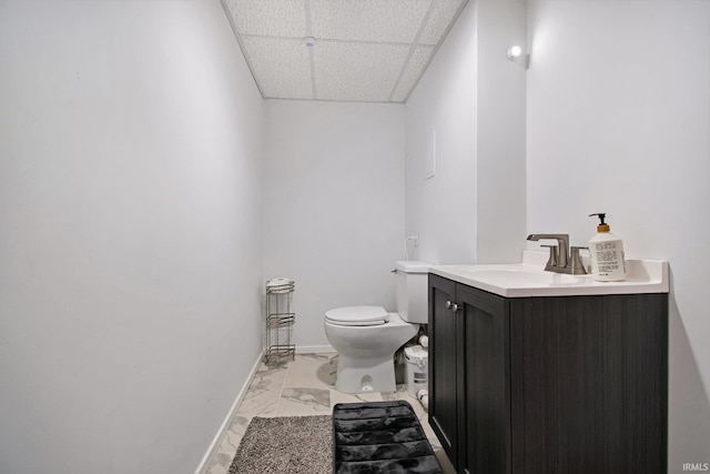 bathroom with a paneled ceiling, vanity, and toilet