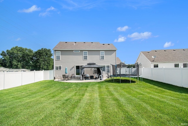 back of house featuring a trampoline, a yard, a patio, and a gazebo