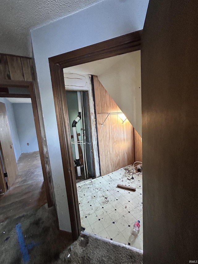 hallway featuring a textured ceiling and wooden walls