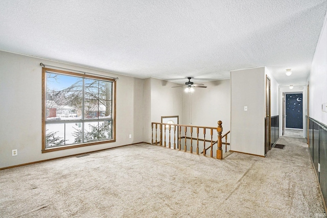 empty room featuring a textured ceiling, light carpet, and ceiling fan