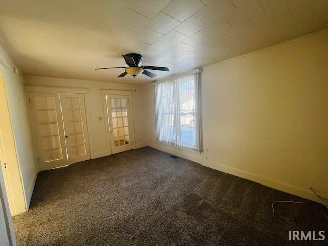 empty room featuring ceiling fan and dark carpet