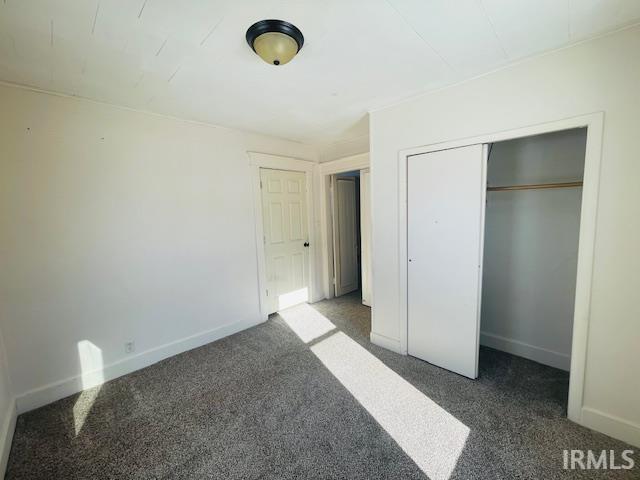 unfurnished bedroom featuring a closet and dark colored carpet