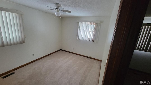 empty room featuring a textured ceiling, light carpet, and ceiling fan