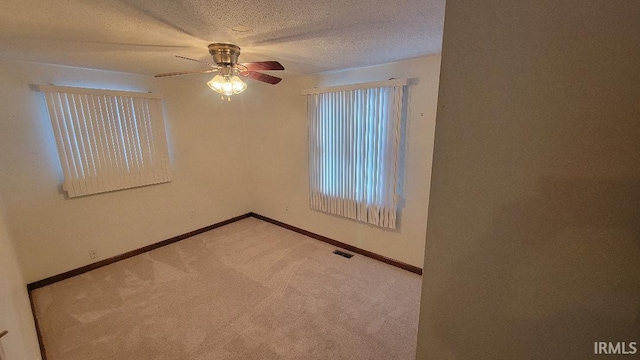 empty room featuring a textured ceiling, ceiling fan, and light carpet