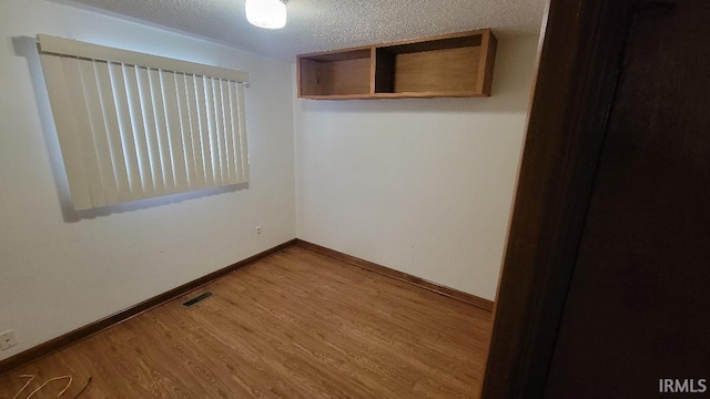 empty room with a textured ceiling and hardwood / wood-style flooring