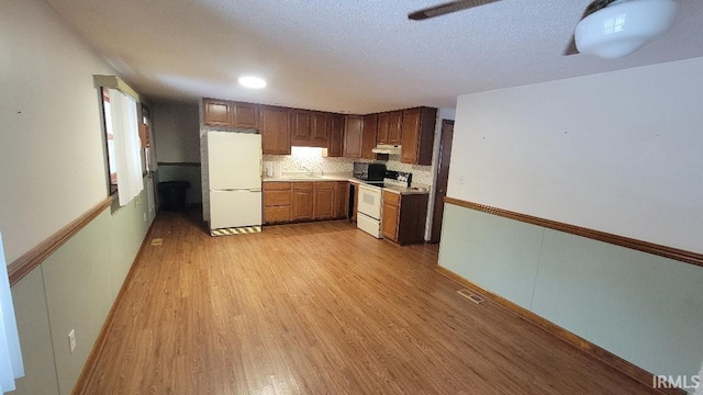 kitchen with white appliances, light wood-type flooring, tasteful backsplash, and sink