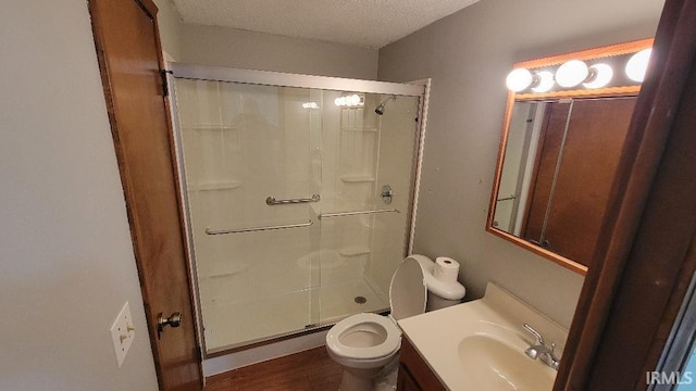 bathroom with a textured ceiling, a shower with shower door, toilet, wood-type flooring, and vanity