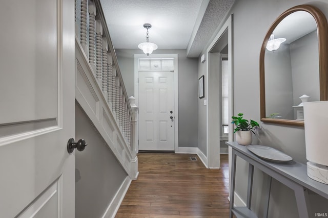 foyer entrance featuring a textured ceiling and dark hardwood / wood-style floors