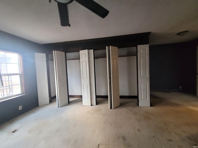 unfurnished bedroom with multiple closets, ceiling fan, and light carpet