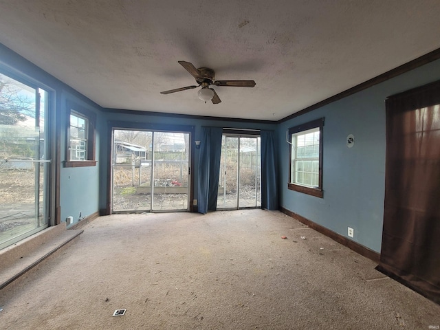 spare room featuring a wealth of natural light, ceiling fan, carpet, and ornamental molding