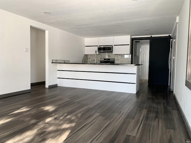 unfurnished living room with a barn door and dark hardwood / wood-style floors