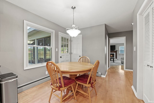 dining space with a baseboard heating unit and light hardwood / wood-style floors