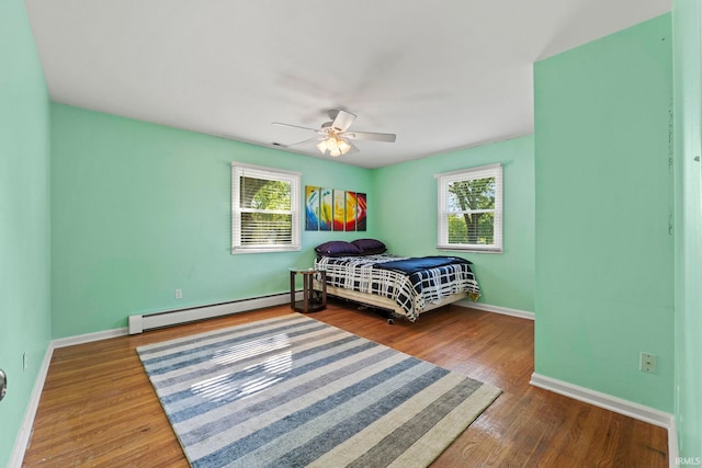 bedroom featuring ceiling fan, hardwood / wood-style flooring, and a baseboard heating unit