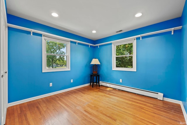 empty room featuring hardwood / wood-style floors and a baseboard radiator