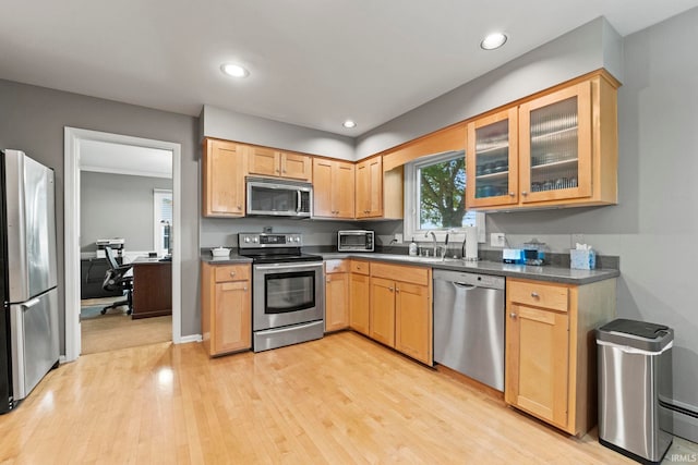 kitchen featuring stainless steel appliances, light brown cabinets, sink, and light wood-type flooring