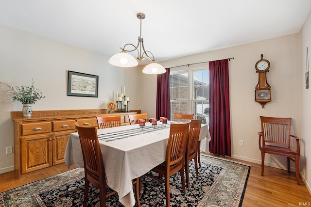 dining area featuring light wood-type flooring and a notable chandelier