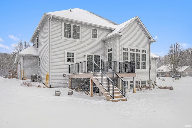 snow covered back of property featuring a wooden deck