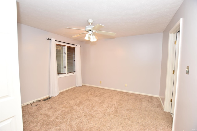 spare room featuring light colored carpet and ceiling fan