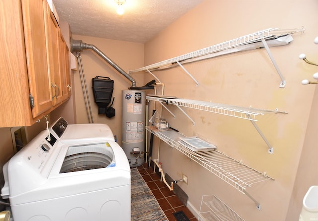 laundry room featuring a textured ceiling, cabinets, independent washer and dryer, dark tile patterned flooring, and gas water heater